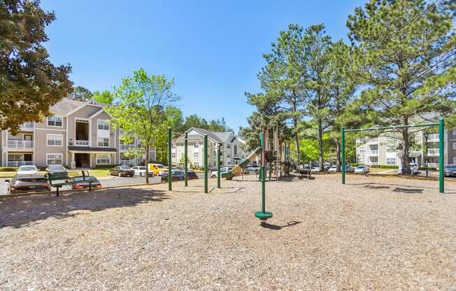 A playground with a green pole in the middle of the gravel area.