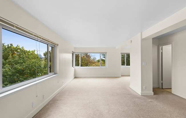 the living room has large windows and a carpeted floor