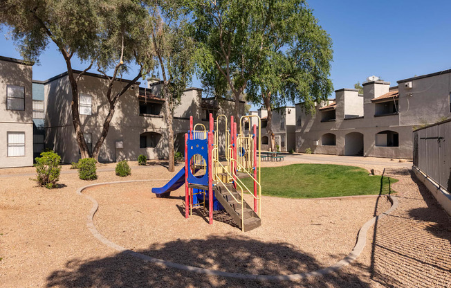a playground with a swing set and slides in front of a building
