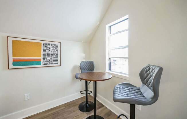 A small table with two chairs in front of a window.