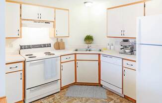 A kitchen with white appliances and wooden cabinets.