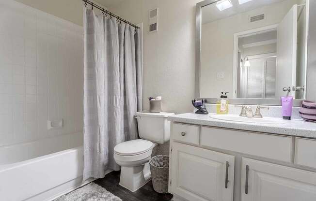 A white bathroom with a toilet, sink, and bathtub.at 2400 Briarwest Apartments, Houston, 77077