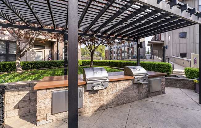 bbq area with a stone wall and a pergola with stainless steel