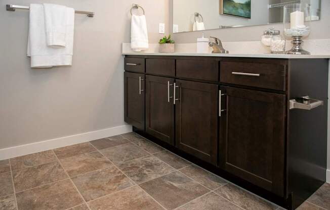 A bathroom with a brown cabinet and a tiled floor.