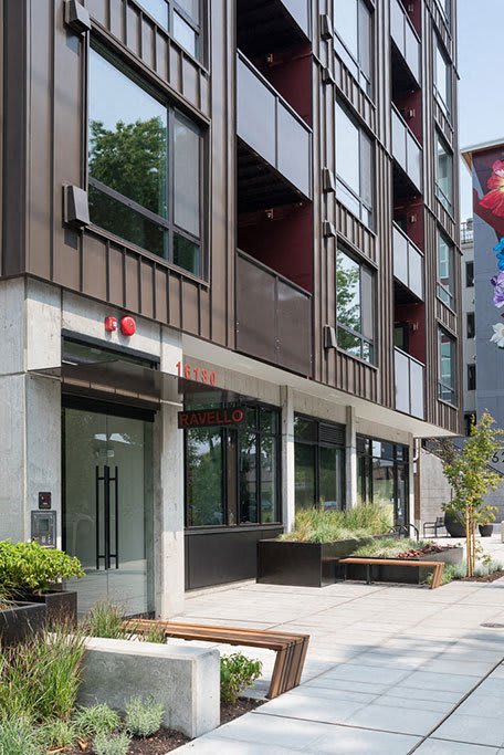 A modern building with a glass entrance and a red sign  at Ravello Apartments, Redmond, WA