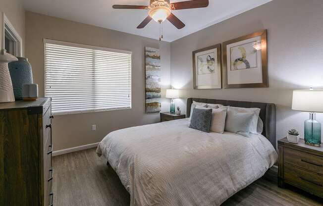 A bedroom with a bed, nightstand, and a ceiling fan.