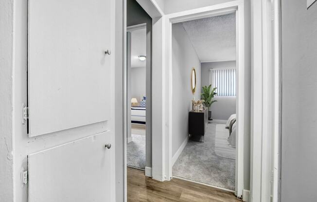 an open doorway into a bedroom with a bed and a mirror