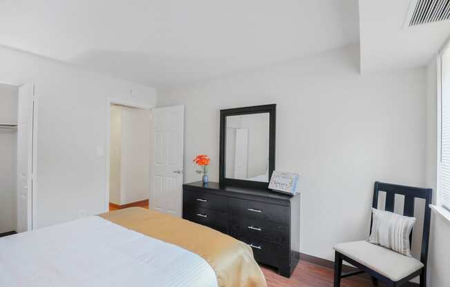 A bedroom with a bed, dresser, mirror, and chair.