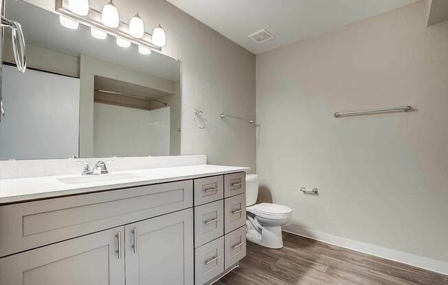 A bathroom with a toilet, sink, and mirror at Sterling Point Apartment Homes, Phoenix