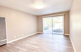 an empty living room with hardwood flooring and a sliding glass door