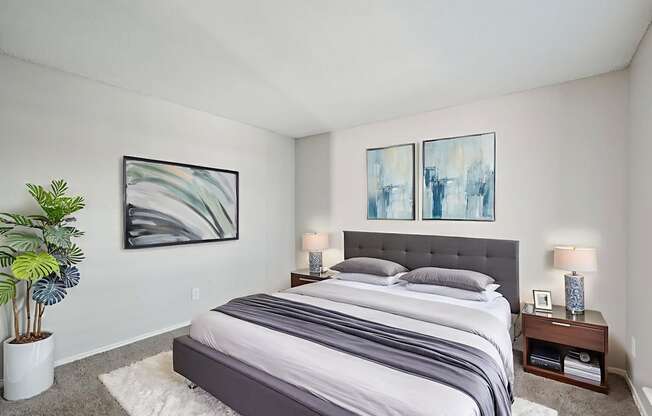 A bedroom with a large bed and two framed artworks on the wall.