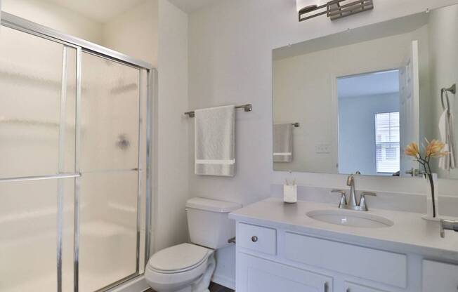 A white bathroom with a toilet, sink, and shower.