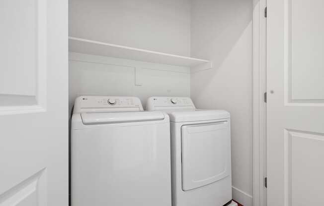 a washer and dryer in a laundry room with white walls and white doors