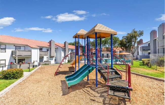a playground with a swing set and slides at an apartment complex