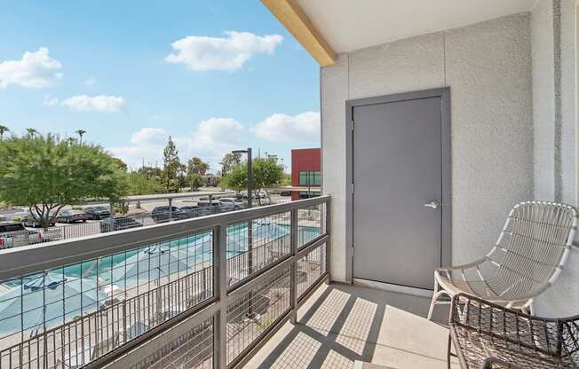 A balcony with a chair and a pool in the background.
