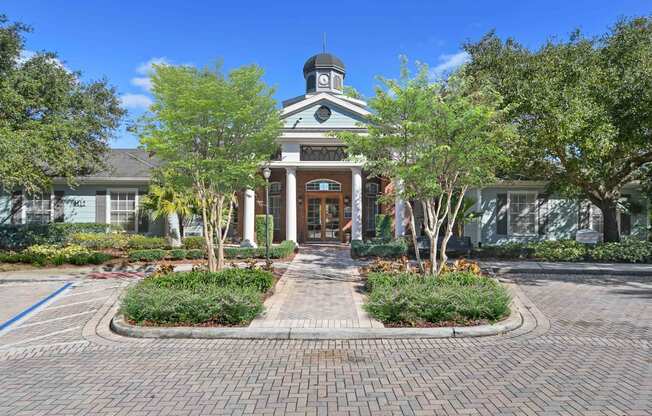the front of a house with trees and a brick sidewalk
