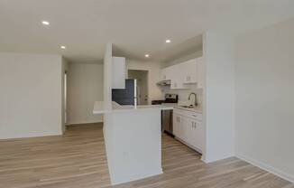 A kitchen with white cabinets and a wooden floor.