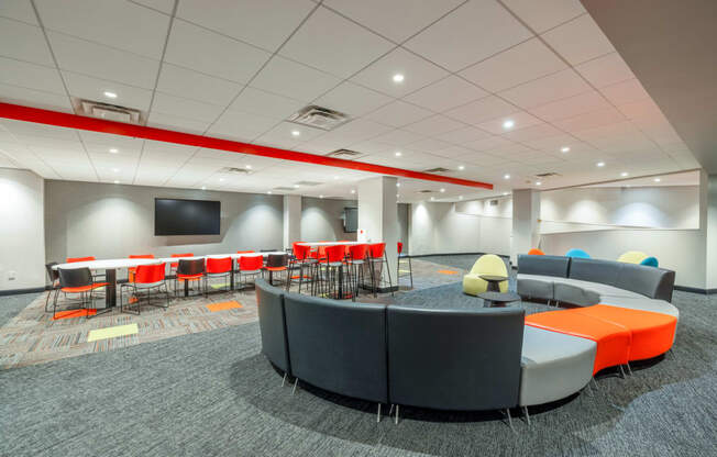 a lounge area with chairs and tables and a tv