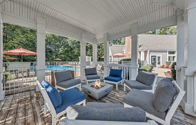 a covered porch with couches and chairs and a fire pit