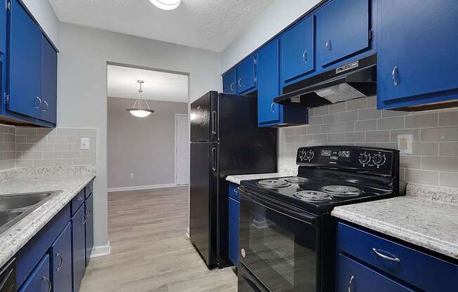 A kitchen with blue cabinets and black appliances.