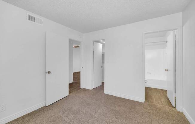 A white room with carpeted flooring and two doors at Urban WalkApartments on 6th Avenue, Phoenix 85016