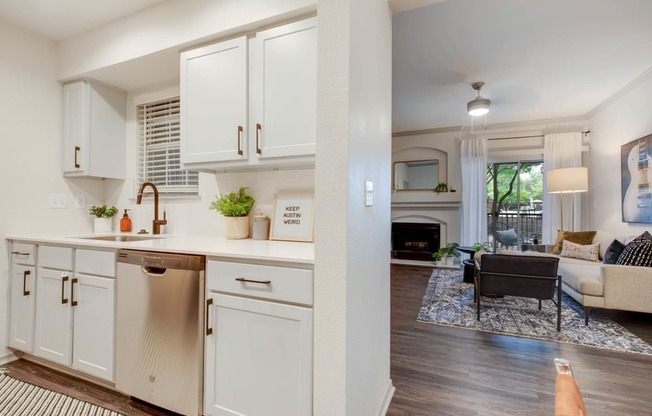 a kitchen with white cabinets and a living room with a couch at The Olivine, Austin, 78727