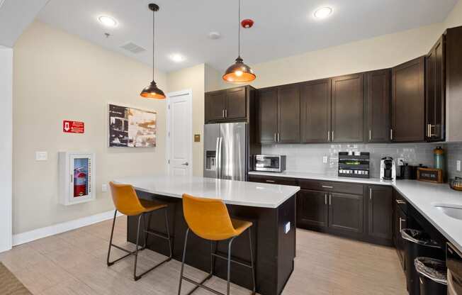 a kitchen with a large island with two orange chairs