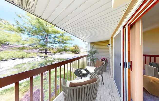 A balcony with a table and chairs overlooking a garden.