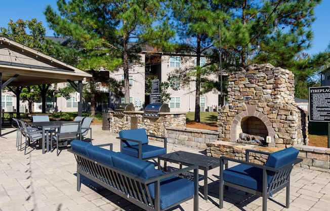 A stone fireplace is surrounded by blue chairs and tables.