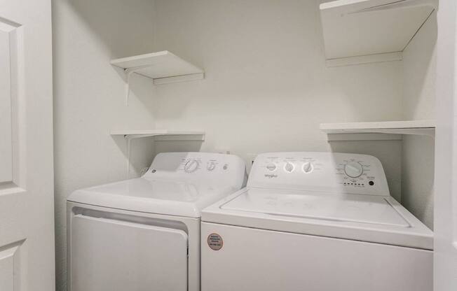 Two white washing machines in a small laundry room.