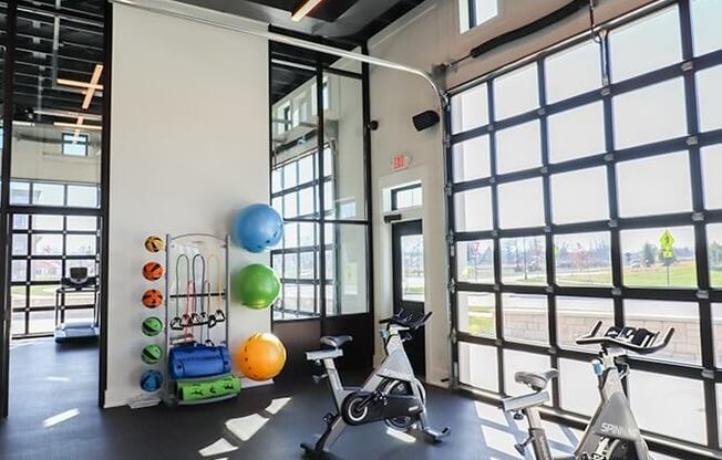 a workout room with exercise bikes and windows