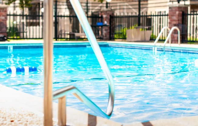 A pool with a diving board and a metal railing.