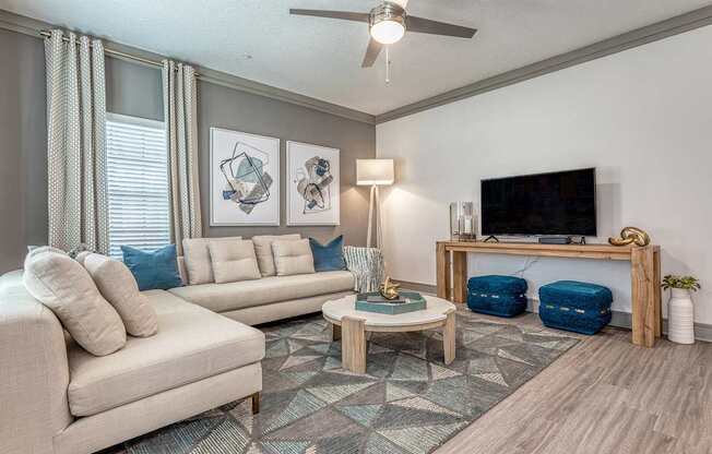 A living room with a beige couch, a coffee table, and a television.