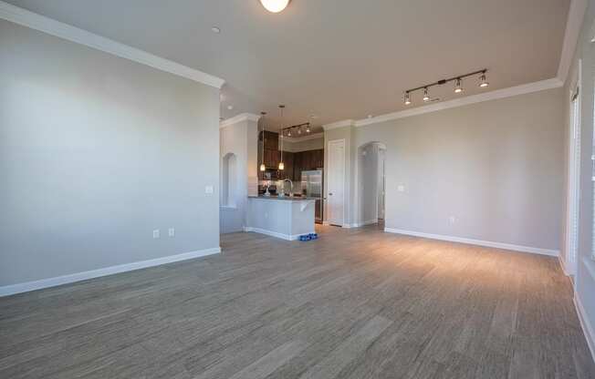 Living room with hardwood flooring facing kitchen with stainless steel appliances