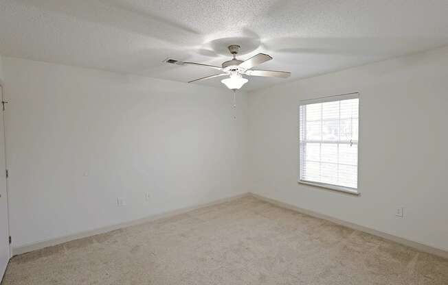 A room with a ceiling fan and a window.