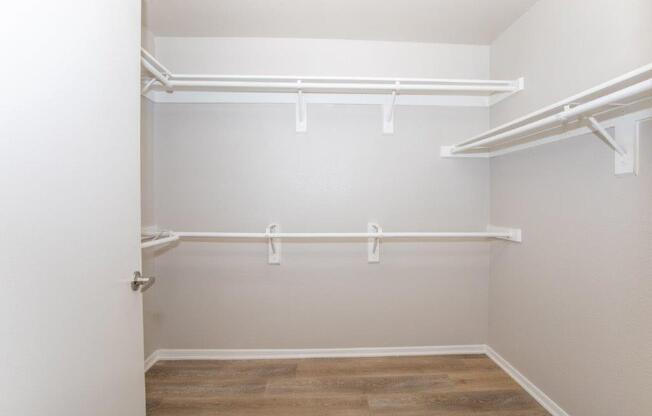 A white closet with a door and shelves.