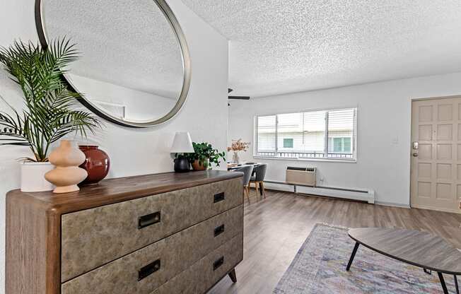 a living room with a dresser and a round mirror