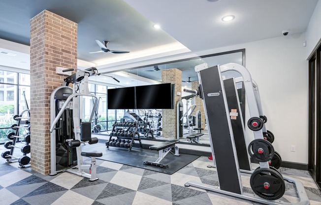 a gym with weights and a tv on the wall