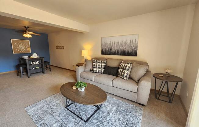 A living room with a couch, coffee table, and a painting on the wall.