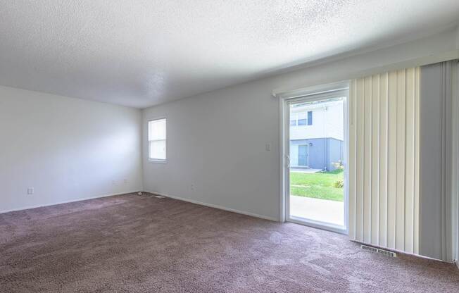 A room with a carpeted floor and a sliding glass door at Spring Creek Townhomes Apartments, Springfield, IL 62702