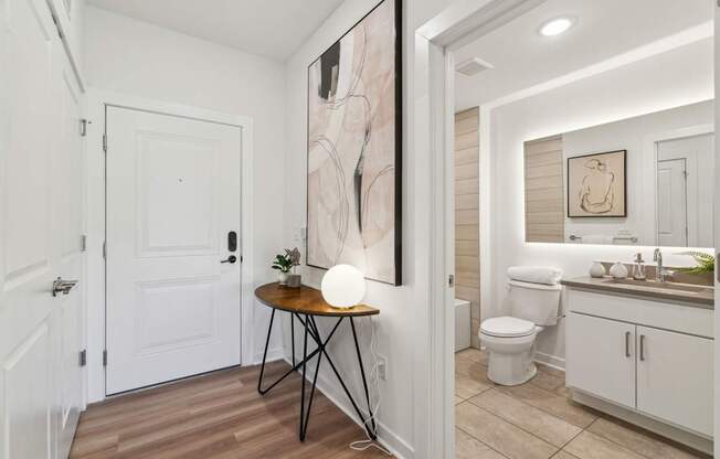 A bathroom with a toilet, sink, and a painting on the wall.