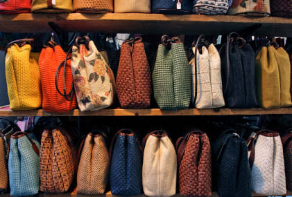 a row of different colored bags on a shelf