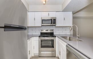 a kitchen with white cabinets and stainless steel appliances