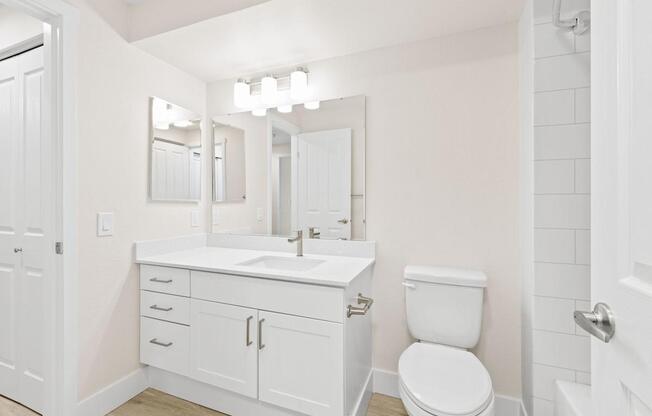 A white bathroom with a toilet, sink, and mirror.