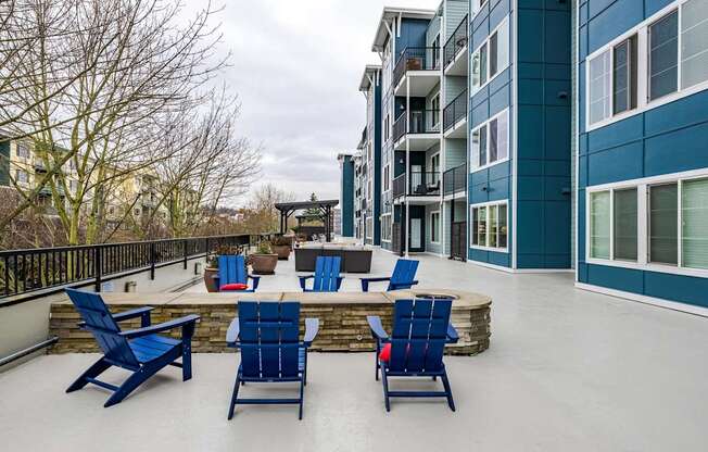 A patio with blue chairs and a table.