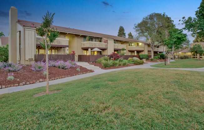 an exterior view of a house with a yard and sidewalk at Summerwood Apartments, Santa Clara