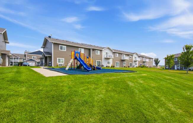 A playground with a blue slide is in the foreground of a residential area.