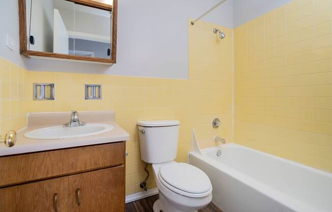 full bathroom with brown cabinet and yellow tile walls