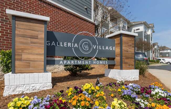 a sign that says galeria village apartment homes with flowers in front of it