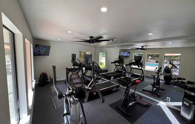 A gym with a row of exercise bikes and a television.